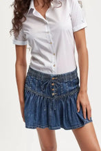 Blue denim mini skirt with gathered waist, button closures, and ruffled hem in a casual denim skirt style