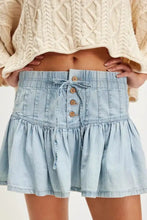 Light blue mini denim skirt with gathered waist wooden buttons and ruffled hem in a buttoned ruffled mini denim skirt style