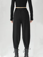 Black high-waisted buckle detail tapered pants in polyester fabric with elastic waistband and drawstring cuffs for perfect fit