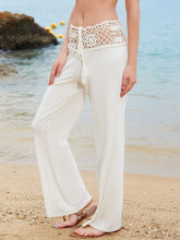 Cream-colored wide leg pants featuring a crochet waist wide lace waistband with tassels for a beach look