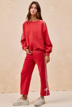 Red athletic sweatshirt with white side stripes and drawstring cuffs paired with bow details fleece sweatpants