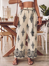 Cream-colored boho print wide leg pants with black floral lace patterns and elastic waistband with drawstring tie
