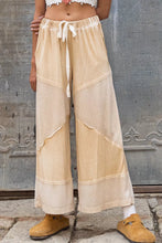 Beige pol elastic waistband wide leg pants with patchwork textures, subtle distressing, and white drawstring waistband