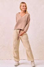 Beige ribbed knit v neck sweater with long sleeves paired with drawstring striped twill barrel pants