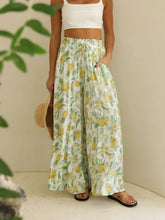 Light green drawstring paperbag waist wide leg pants with yellow pineapple and leaf tropical print motifs