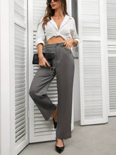 A sleek black clutch with a delicate chain strap complements high waist wide leg pants for a stylish look