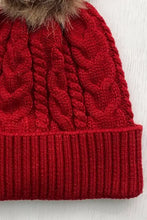 Red cable-knit cuffed hat with brown faux fur pom-pom