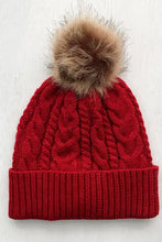 Red cable-knit cuffed hat with brown faux fur pom-pom