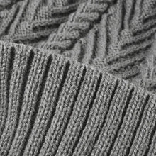 Close-up of cable knit solid color hat with gray ribbed fabric and pompom