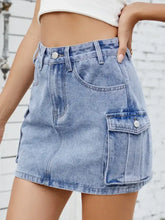 Light-wash denim cargo skirt with two large cargo pockets and button closure in a casual denim skirt style