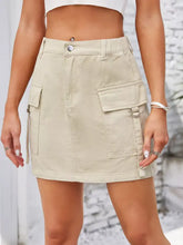 Beige cargo denim skirt featuring multiple pockets and button closure for casual wear