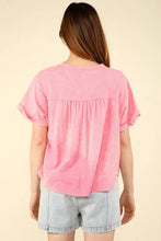 Woman in casual fit pink notched short sleeve top in washed knit fabric with denim shorts