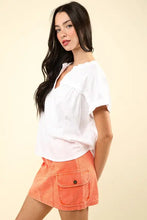 Woman in casual fit nochted short sleeve top with orange mini skirt