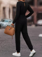 Back view of black long-sleeved jumpsuit with back cutout, elastic waistband, machine wash cold