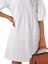 A white tiered cotton dress with puffed sleeves and a flared skirt contrasting a casual denim mini dress style