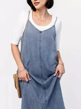 Casual washed denim cami maxi dress featuring blue denim overalls with gold chain straps and a white top underneath