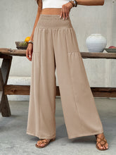 Beige smocked waist wide leg pants with a high smocked waist and two front patch pockets in lightweight fabric