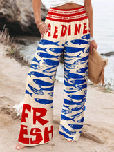 Plus size printed cream wide leg pants with bold blue fish pattern and red fresh lettering on waistband and hem