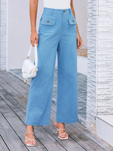 Light blue high waist wide leg pants made of denim with front pockets and gold tone buttons