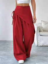 Red wide-leg wrap-front wide-leg pants with draped asymmetrical design and matching fabric tie at the waist