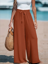 Rust-colored plus size wide leg pants with a tied drawstring waist and high-waisted design for comfortable wear