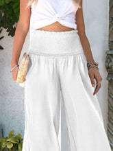 White high-waisted wide-leg pants featuring a smocked waist and relaxed flowing fabric as smocked waist pants