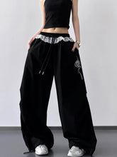 Black wide leg pants with drawstring lace trim waistband and white embroidered rose on the leg