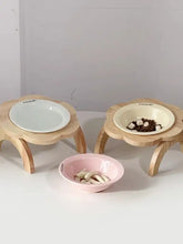 Set of three ceramic pet bowls on wooden stands with kibble
