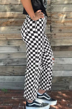 Checkerboard print black and white denim jeans with distressed details ripped knees raw edges and cropped length