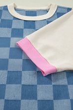 Blue and white checkered long-sleeve top with cream ribbed neckline and pink cuff trim in checkered denim patchwork style