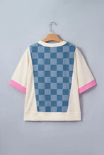 Back view of a cream short-sleeved loose top with blue checkered denim patchwork and pink trim at cuffs and hem