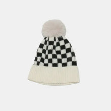 Black and white checkered knit hat with cream pom-pom and folded brim