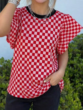 Red and white checkered print ruffle cap sleeve top with black ribbed neckline and round neck design