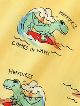 Yellow printed crew neck kids t-shirt with surfing green dinosaur and happiness comes in waves text. Machine wash cold