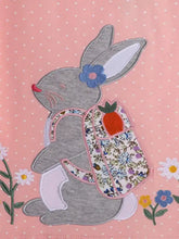 Back of Children’s Rabbit Ruffle Sleeve T-Shirt with gray bunny applique, blue flower ear, floral backpack, orange carrot. Machine wash cold, tumble dry low