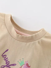 Children’s unicorn print t-shirt, beige cotton with purple laugh script, pink unicorn in green crown. Machine wash cold