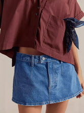 Classic wash denim mini skort in blue denim featuring a buttoned waistband and frayed hem for a casual look