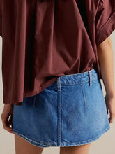 A mid-waisted classic wash denim mini skort in blue with visible stitching details