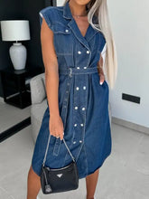 Blue denim dress with collared neck cap sleeve and white buttons paired with black prada chain strap bag
