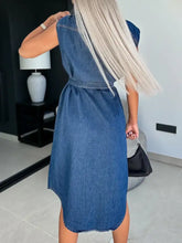 Blue denim dress with collared neck cap, cap sleeves, fitted waistband, and asymmetrical hemline