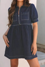 Dark blue denim dress with collared neck half zip, short puff sleeves, and front zipper pockets