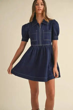 A navy blue denim dress with a collared neck half zip, short puffed sleeves, and two front pockets