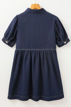 A navy blue denim dress with collared neck half zip, short puffed sleeves, and white stitching along seams