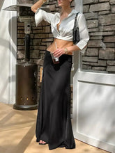 Black satin maxi skirt with a high waist and flowing silhouette paired with a collared long sleeve cropped shirt