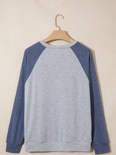A cozy gray and navy blue raglan sleeve sweatshirt featuring embroidered flower patches with soft textured fabric