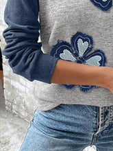Gray raglan long sleeve top features embroidered navy blue floral patch with heart-shaped details and frayed edges