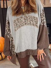A cozy slightly stretchy gray and brown leopard-print patchwork sweatshirt with a bold merry graphic, machine wash cold