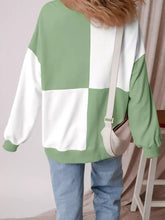 A soft oversized colorblock henley sweatshirt in bold green and white checkerboard pattern with machine wash care instructions