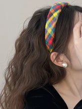 Colorful polyester hair headband with plaid design on wavy dark hair and pearl earring