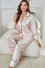 A soft blush pink satin contrast piping button-up top and pants pajama set featuring long sleeve length and black trim